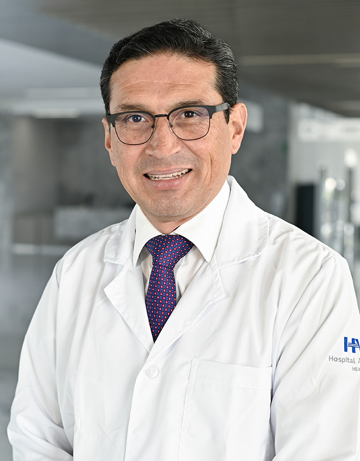 Es la foto de perfil de un ginecólogo y obstetra en Querétaro de Hospital Angeles Centro Sur. Usa una bata blanca, camisa blanca y corbata azul cielo brillante.
