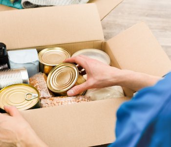 photo of person fill cardboard box with nonperishable foods and canned goods 