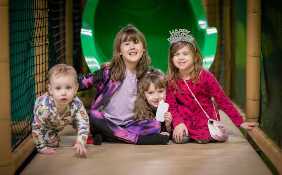 four children sitting at the end of a slide at the Bay View Family YMCA Adventure Center