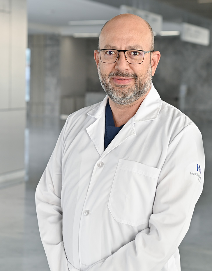 Es la foto de perfil de un urólogo en Querétaro de Hospital Angeles Centro Sur. Usa un traje azul marino con rayas, una camisa blanca y una corbata rojo vino con cuadros blancos.