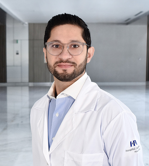 Es la foto de perfil de un cirujano oncológico en Querétaro de Hospital Angeles Centro Sur. Usa un traje gris oscuro y una camisa blanca, tiene barba y está sonriendo.
