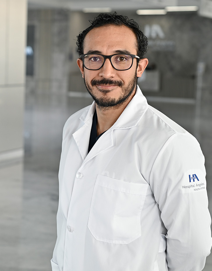 Es la foto de perfil de un urólogo en Querétaro de Hospital Angeles Centro Sur. Usa un uniforme negro, unos lentes cuadrados y un reloj.