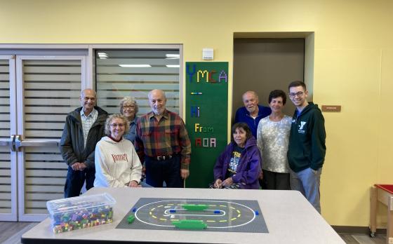 seniors standing in front of a lego wall that that says YMCA written in legos