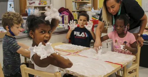 a group of kids at a table doing a craft with shaving cream