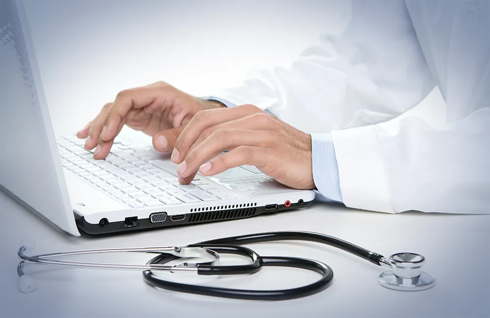 Médico del Hospital Angeles escribiendo el diagnóstico de su consulta médica privada en su computadora buscando la salud y bienestar del paciente