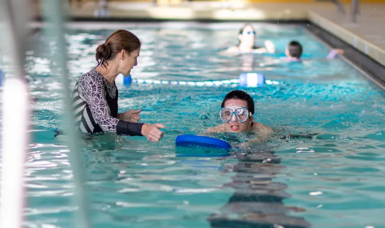 ymca instructor works with member during swim lesson