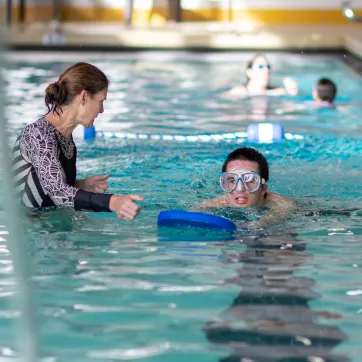 ymca instructor works with member during swim lesson
